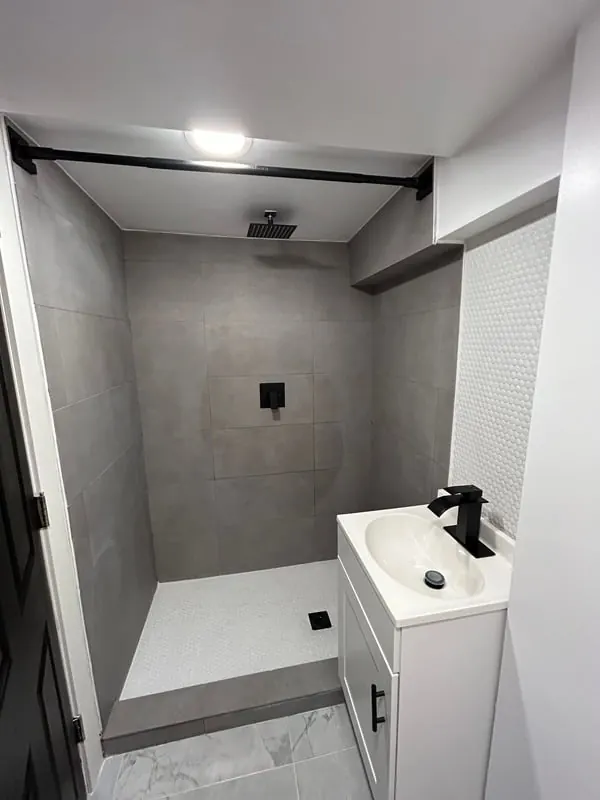 Finished basement bathroom with a gray tile walk-in shower and black fixtures