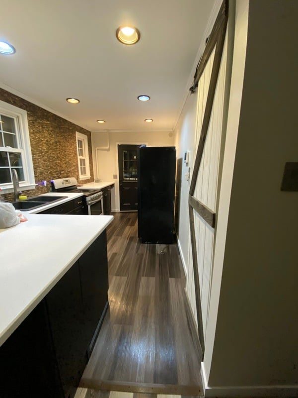 Galley kitchen remodel with white counters, wood-look floors and a sliding barn door