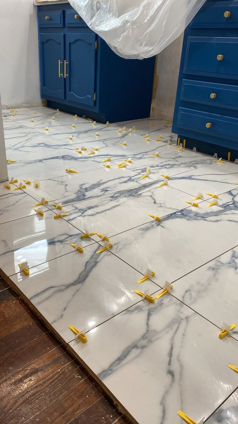Large marble-look floor tiles being set with leveling clips