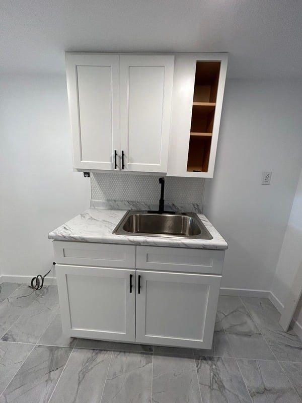 Studio kitchenette with white shaker cabinets and marble-look counter